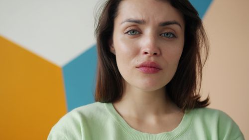 Free Close-up of a young woman with an emotional expression against a colorful wall. Stock Photo
