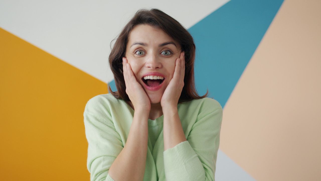 cheerful woman expressing surprise against a colorful geometric backgr