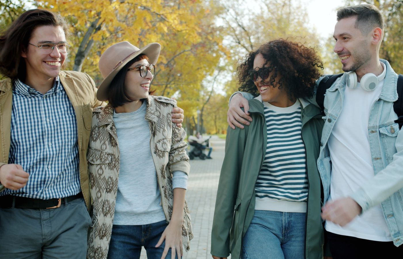 Group of friends laughing and walking in a park on an autumn day.