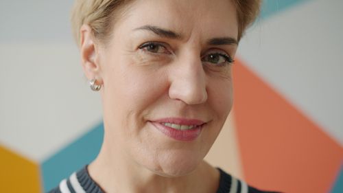 Free Close-up of a smiling mature woman in front of a colorful geometric background. Stock Photo