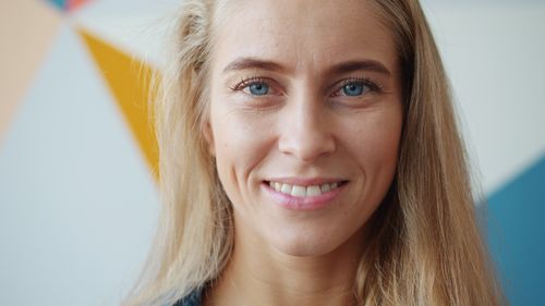 Free Close-up portrait of a smiling blonde woman against a colorful geometric background. Stock Photo