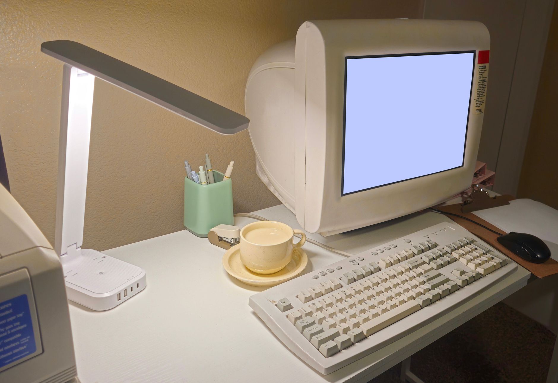 A nostalgic home office featuring a vintage computer, keyboard, and coffee cup.