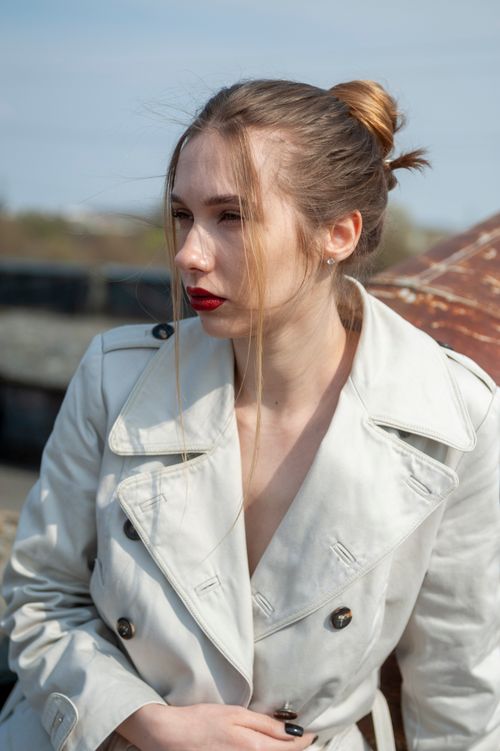 Free A fashionable woman in a white coat poses on a rooftop in Lviv, Ukraine under a clear sky. Stock Photo