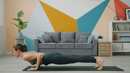 Free A woman doing yoga in a stylish living room with vibrant geometric walls. Stock Photo