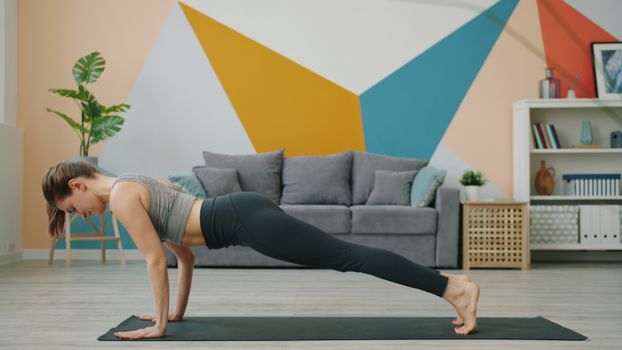 Woman practicing yoga in a modern living room with geometric wall art.