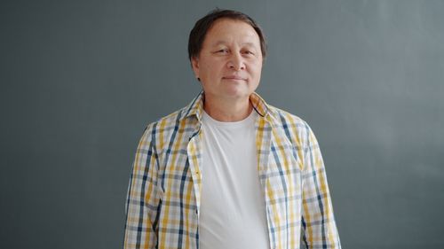 Free Smiling mature man in casual plaid shirt posing confidently indoors. Stock Photo