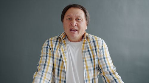 Free A man in plaid shirt expressing surprise against a gray background. Stock Photo