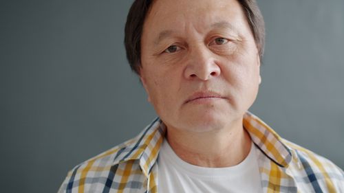 Free Close-up portrait of a mature man wearing a checked shirt against a gray background. Stock Photo