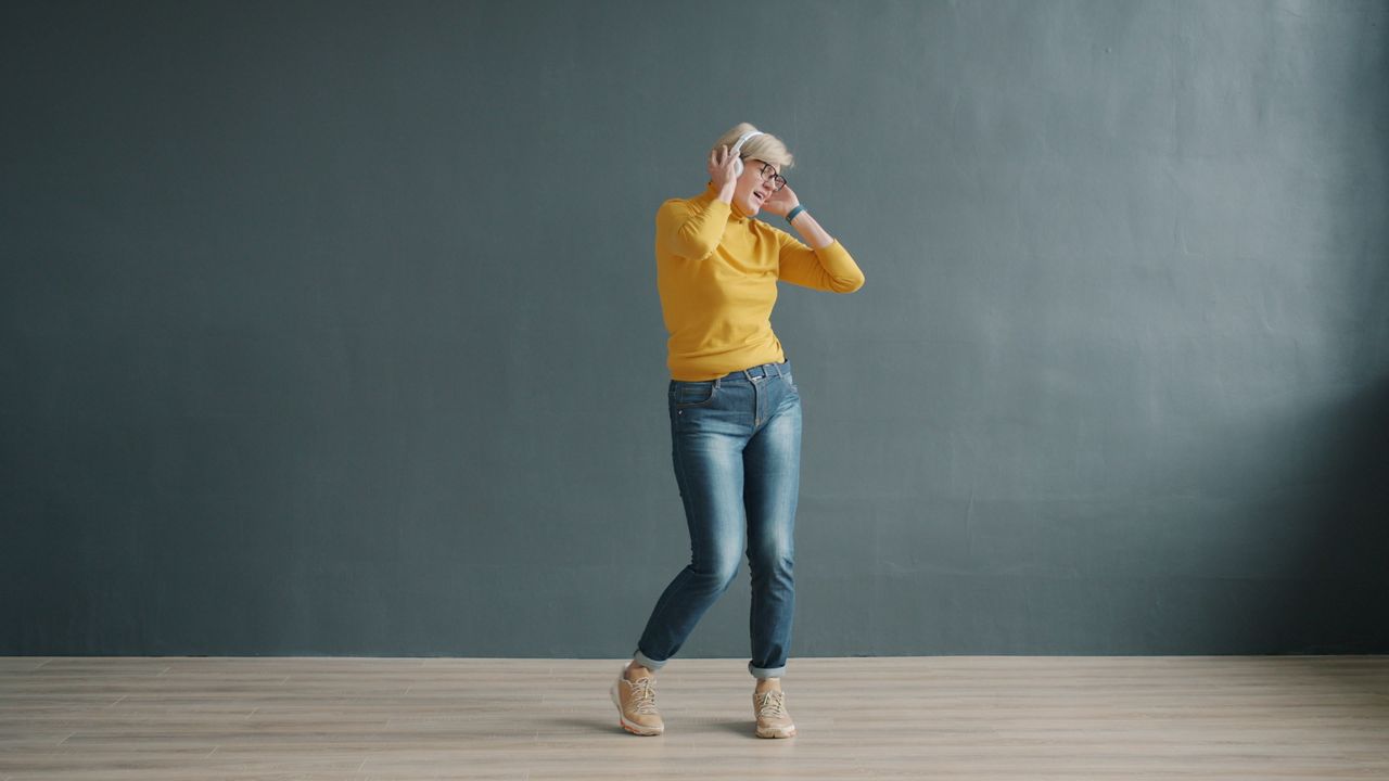woman joyfully dancing in casual attire listening to music indoors