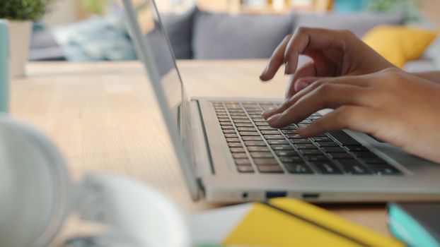 Hands typing on a laptop keyboard indoors with blurred background and natural lighting.