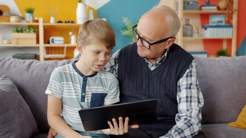 Free Elderly man and young boy enjoying time with a tablet on a cozy couch. Stock Photo