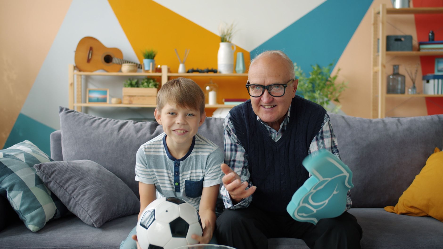 Family watching a JioHotstar football match on a large smart television with snacks in an Indian home