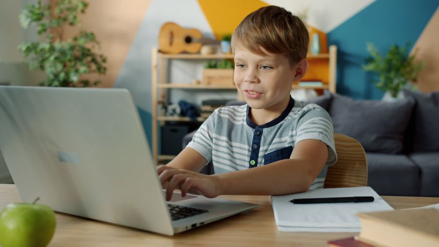 A happy, motivated child learning online with a laptop
