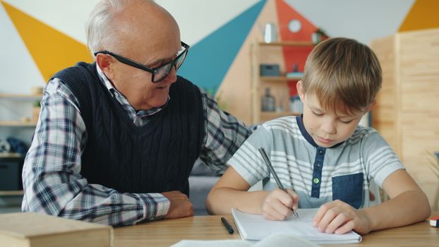 Elderly man assisting young boy with school work at home.