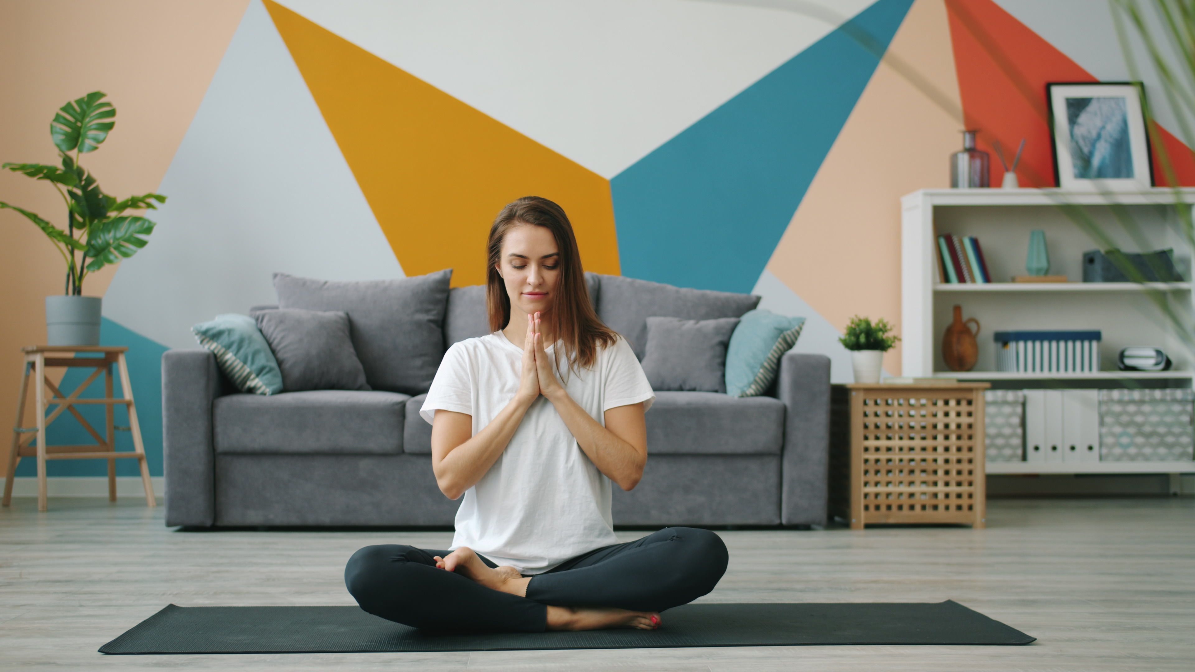 Woman practicing yoga on a mat in a stylish, geometric-themed living room.
