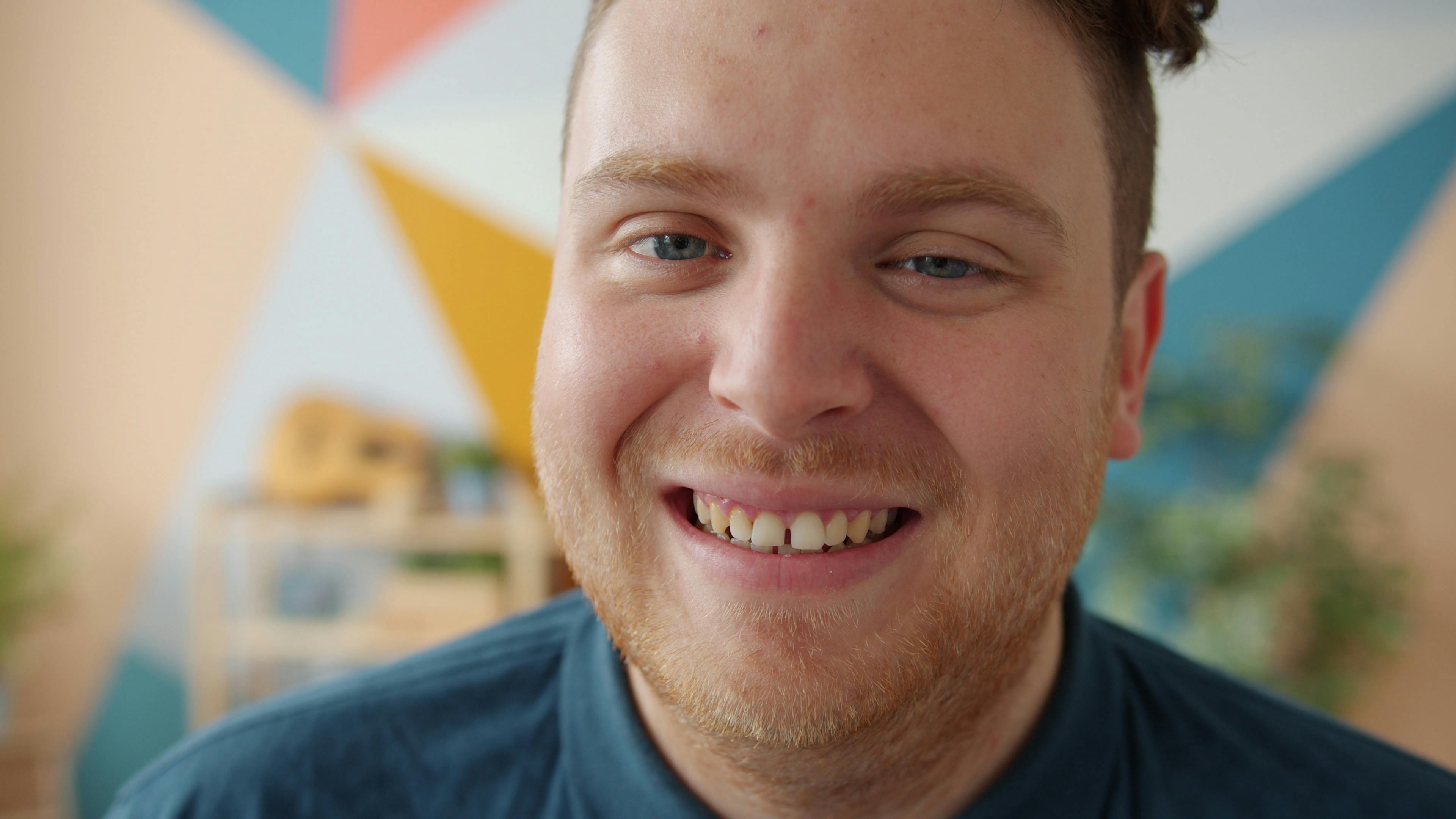 Portrait of a smiling man indoors with a colorful geometric background.