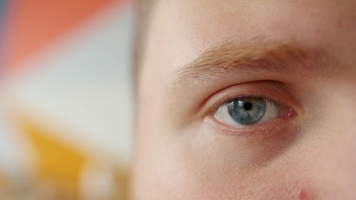 Free Detailed close-up of a blue eye with a colorful blurred background, emphasizing detail. Stock Photo