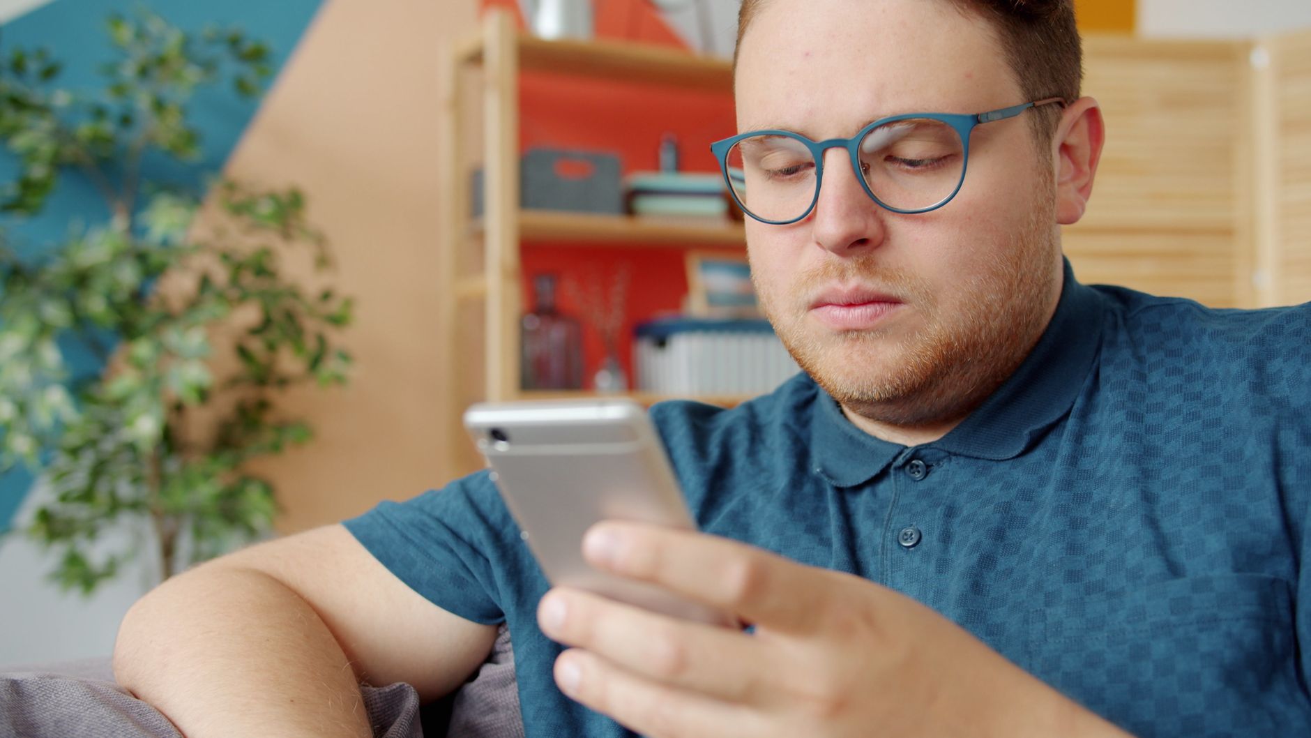 Casual adult man with glasses using smartphone at home.