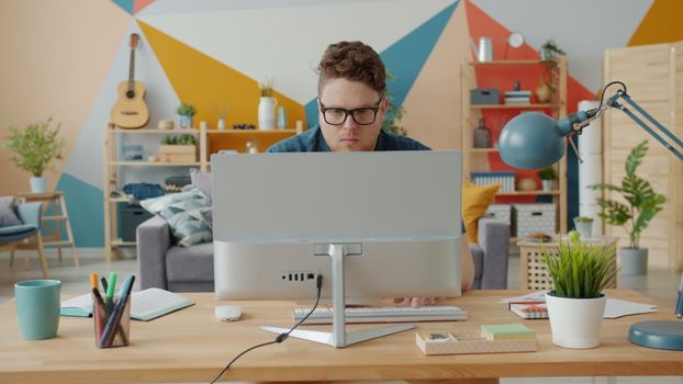 Man working intently at computer in a colorful home office setup.