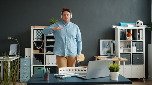 Free Young man enjoys music in modern office setting. Vibrant workspace. Stock Photo