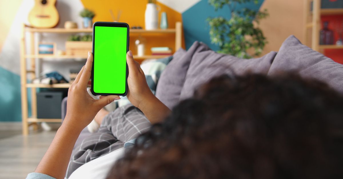 person relaxing on couch ordering food delivery on smartphone at night