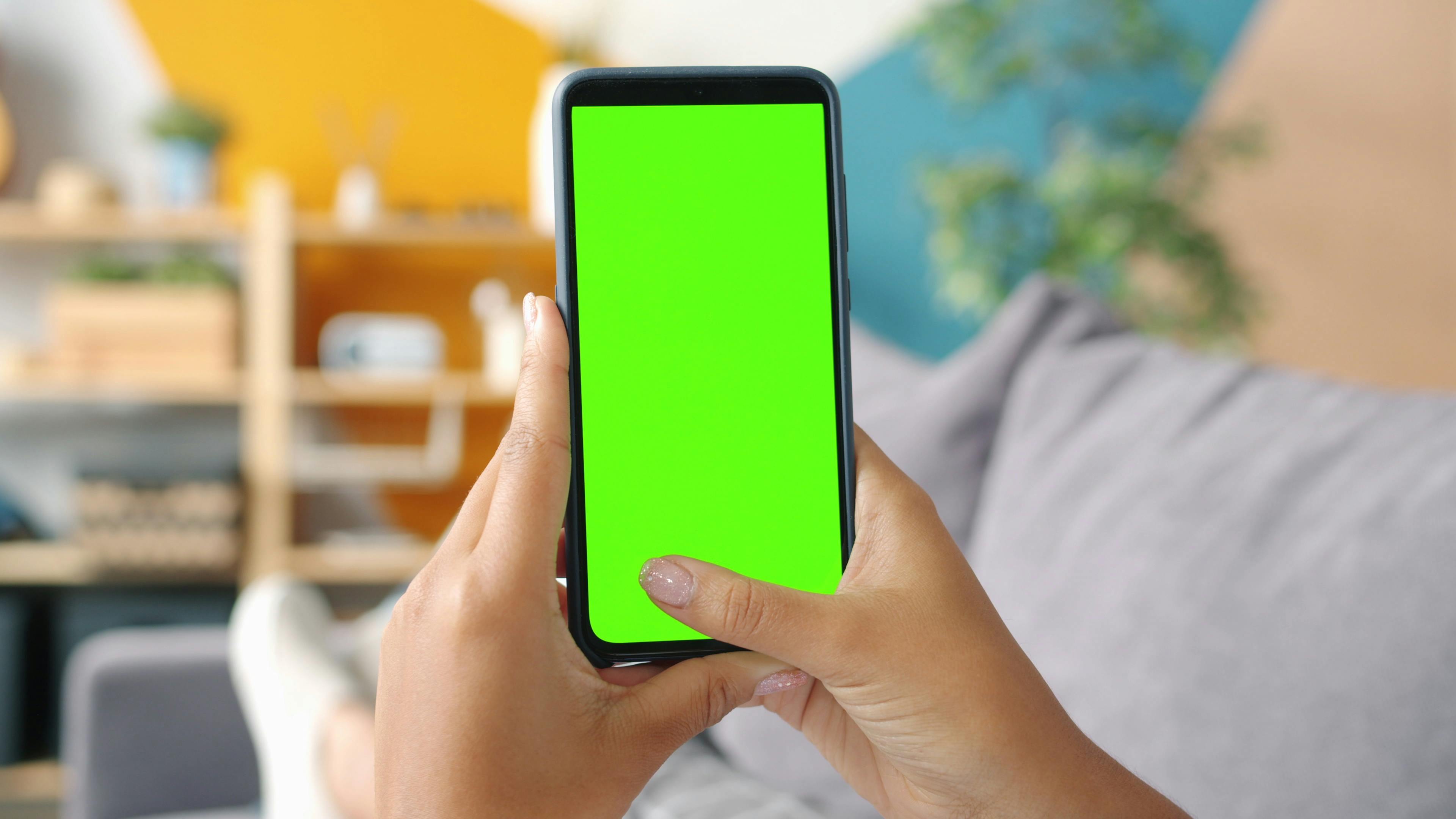 Close-up of hands holding smartphone with green screen for mockup design.
