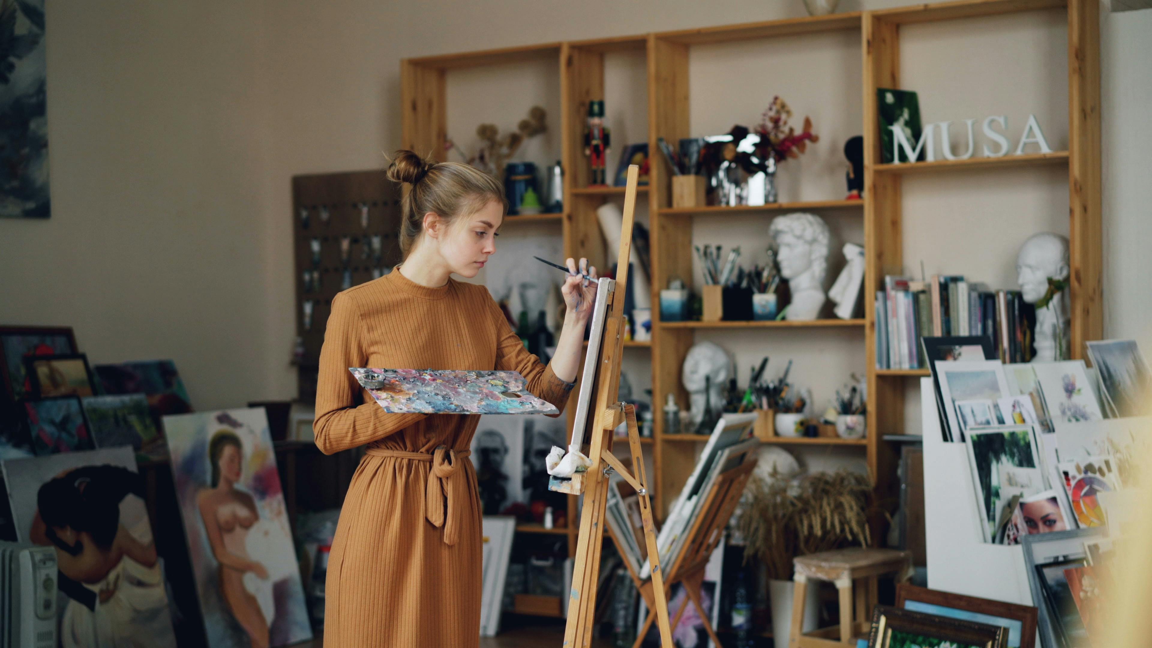 Female artist working on canvas in her art studio.