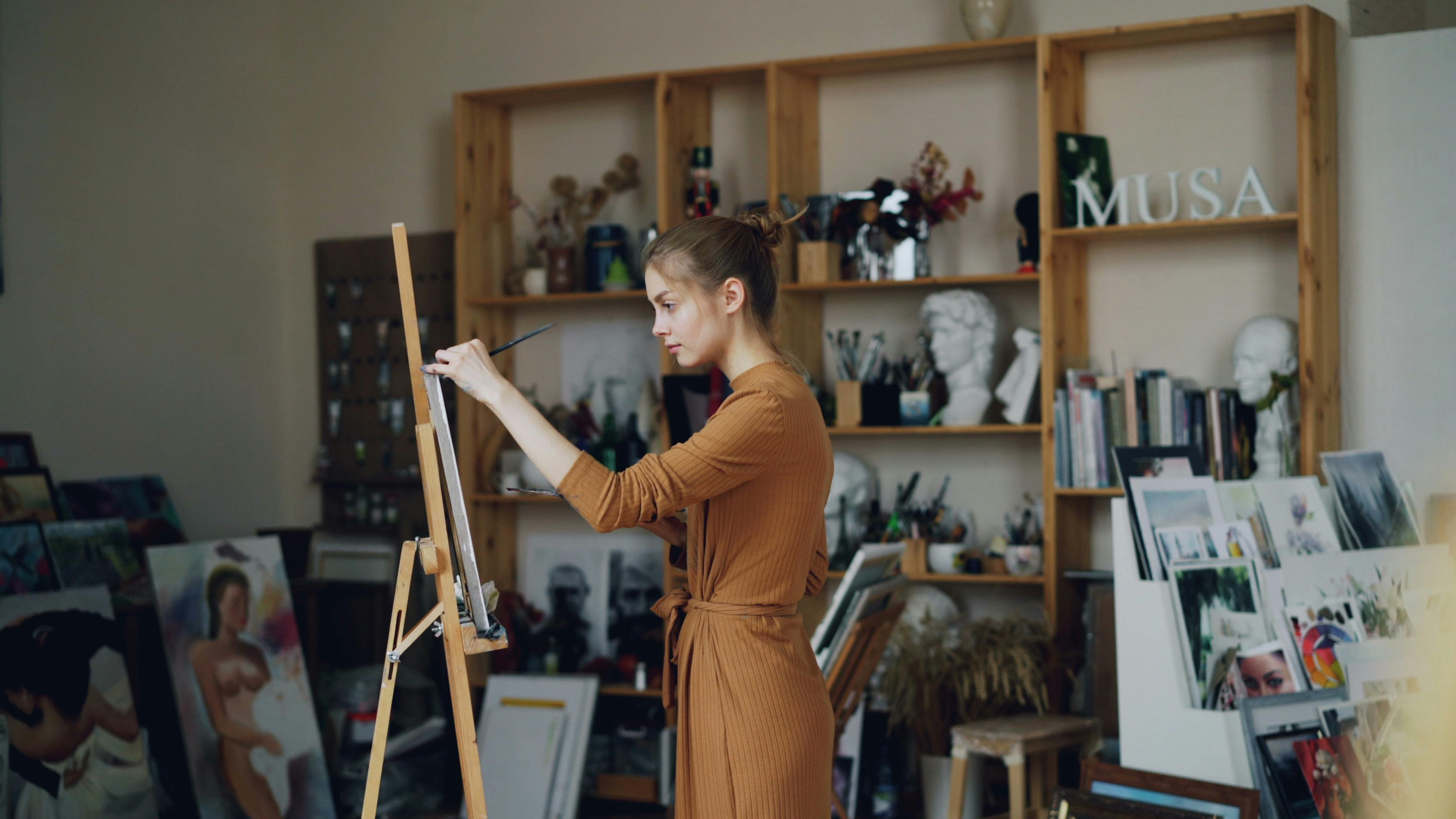 Female artist painting on canvas in creative art studio environment.