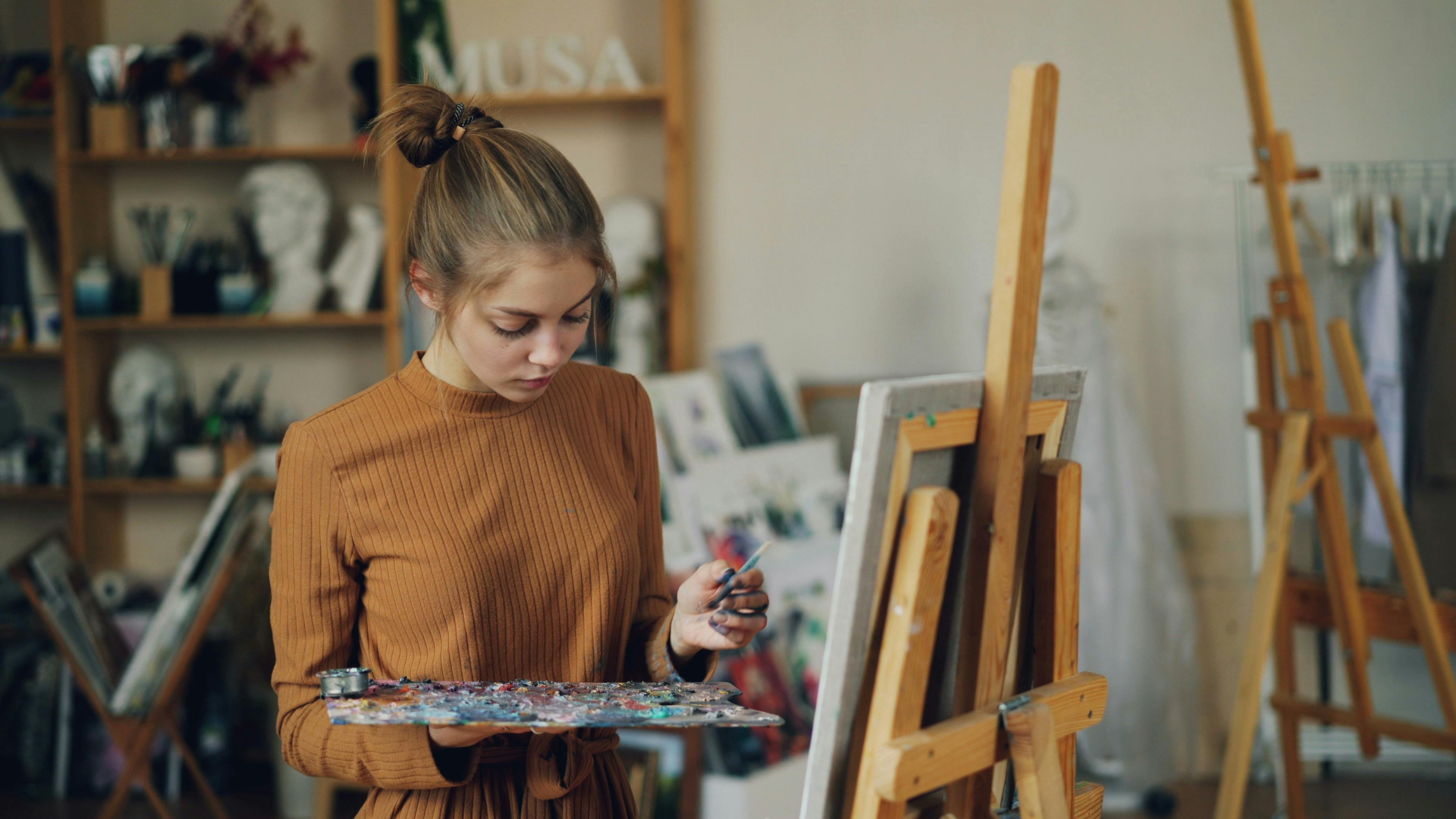 Focused young female artist paints on canvas in an inspiring studio environment.