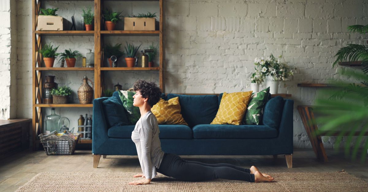 Person doing a gentle yoga pose in their living room, natural lighting, calm expression