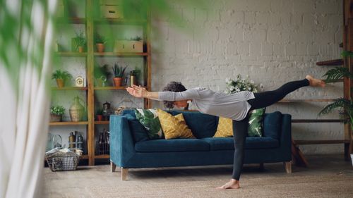 Free Woman practicing yoga in a cozy and stylish living room setting. Stock Photo