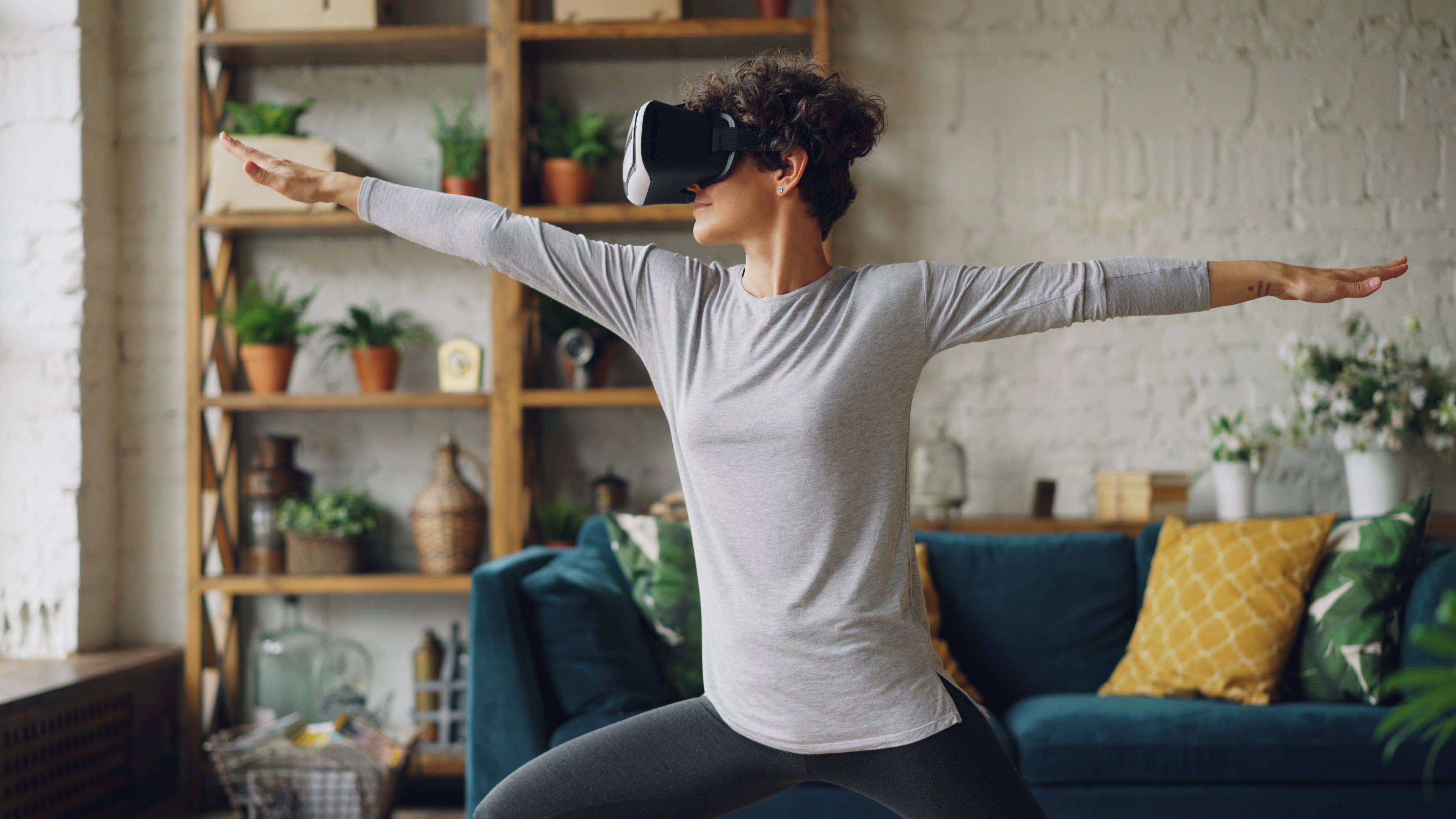 Woman performing yoga with VR headset in stylish indoor setting.