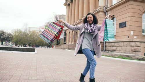 Free Happy woman holding shopping bags outdoors in urban setting. Stock Photo