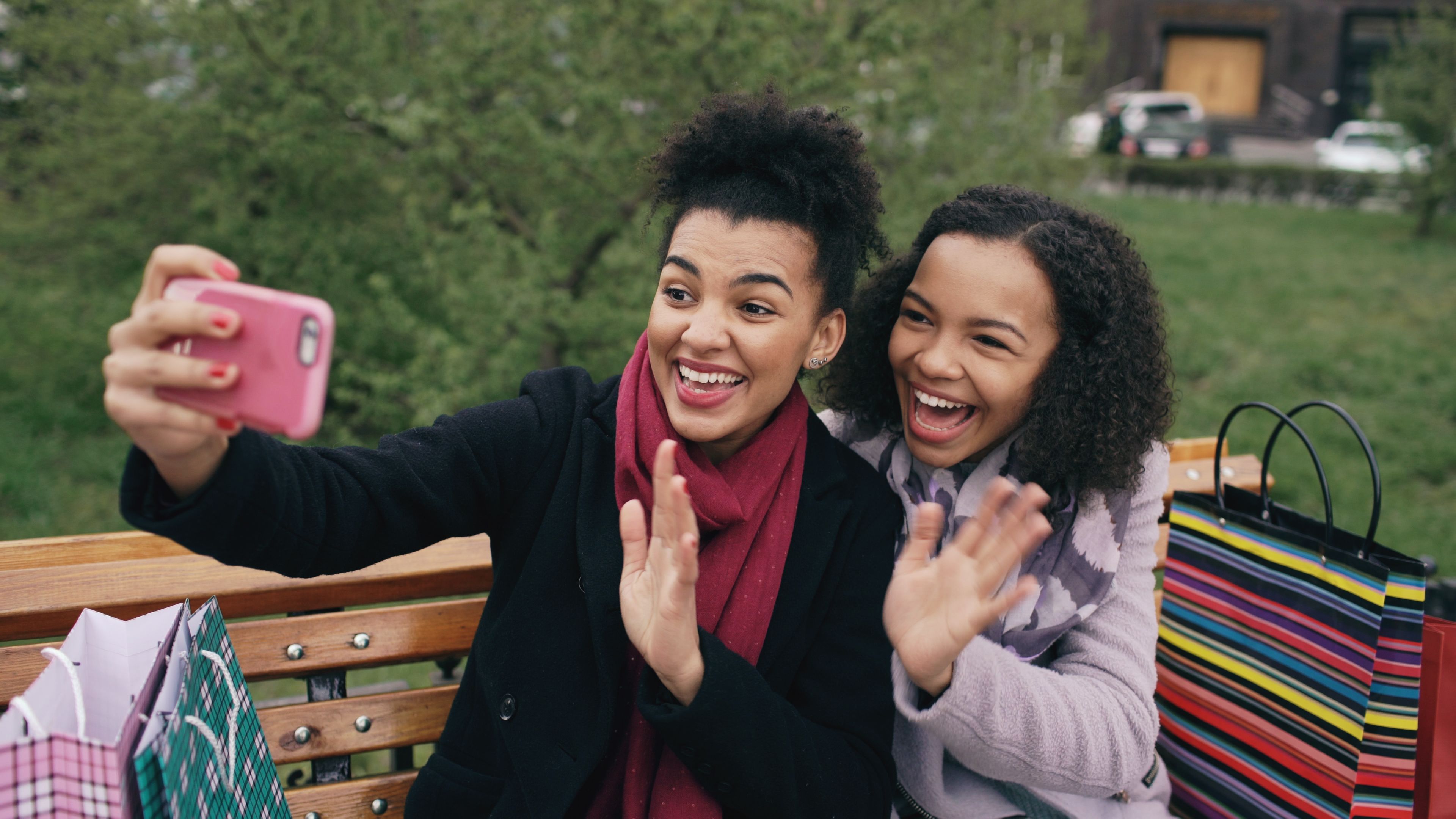 Two smiling women capture joyful memories with a selfie in a bright outdoor setting.