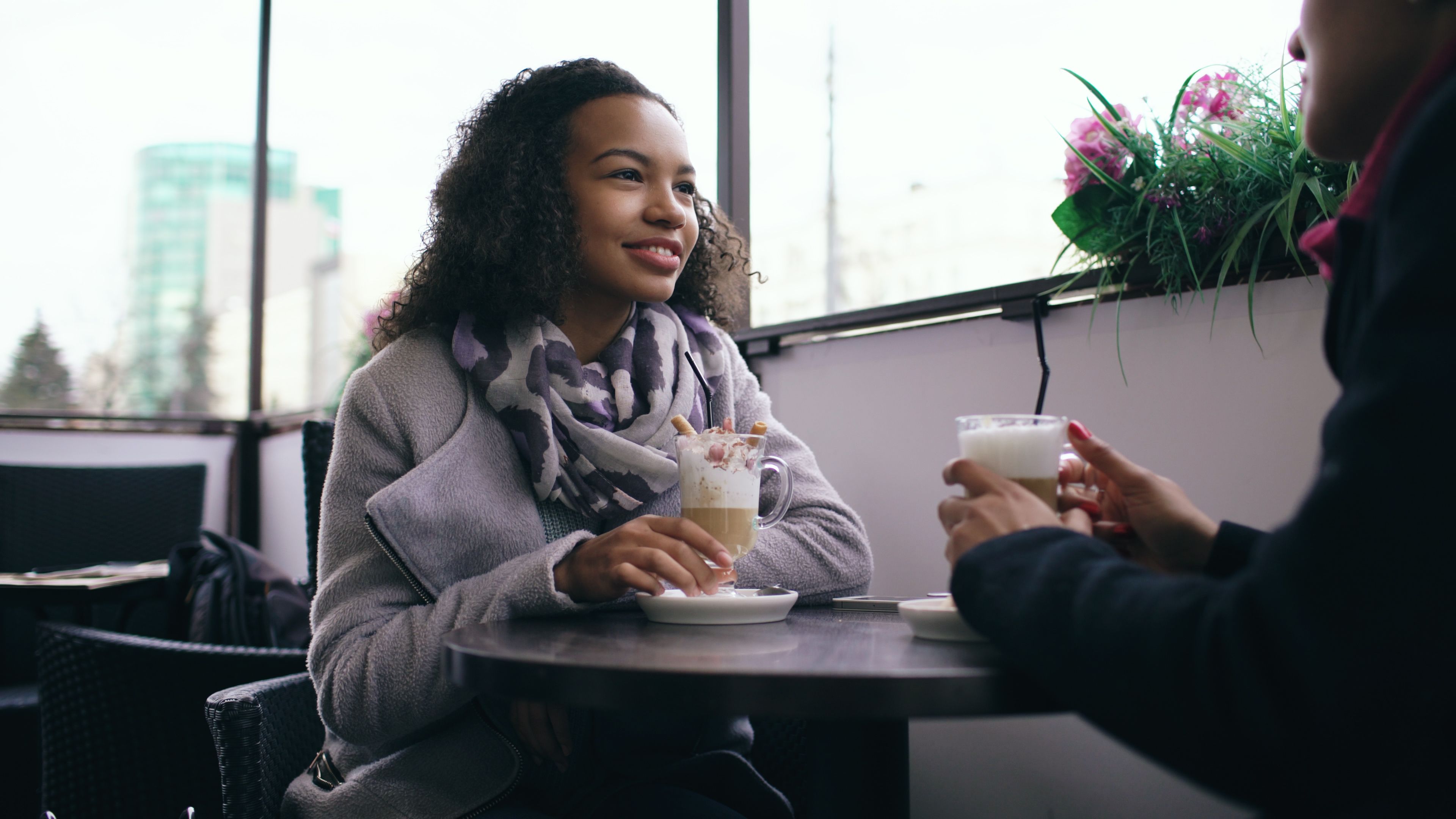 Two adults enjoying coffee and conversation in a relaxed cafe setting.