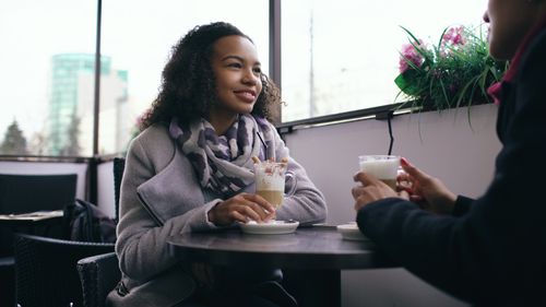 Free Two adults enjoying coffee and conversation in a relaxed cafe setting. Stock Photo