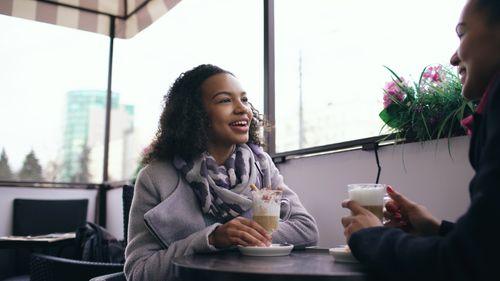 Free Two women enjoying coffee and conversation at an outdoor cafe. Stock Photo