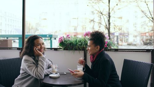 Free Two women enjoying coffee and chatting at an outdoor cafe setting. Stock Photo