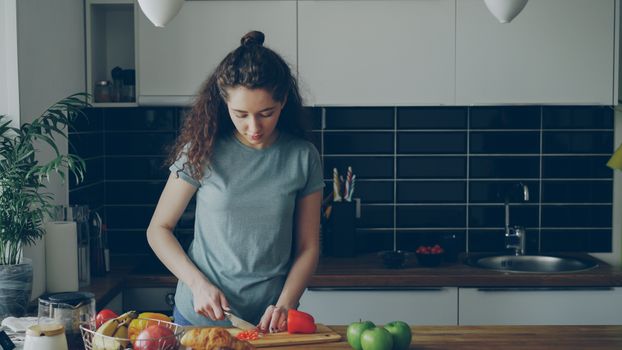 Young woman preparing food in a modern kitchen setting, cutting vegetables.