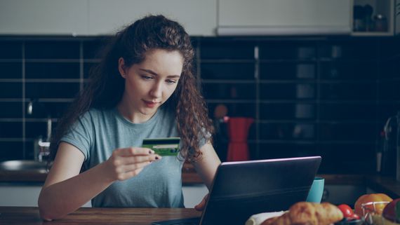 Customer making an online purchase with a laptop and credit card in a kitchen