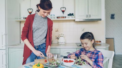 Free A mother and daughter enjoy preparing a fresh salad together in their kitchen. Stock Photo
