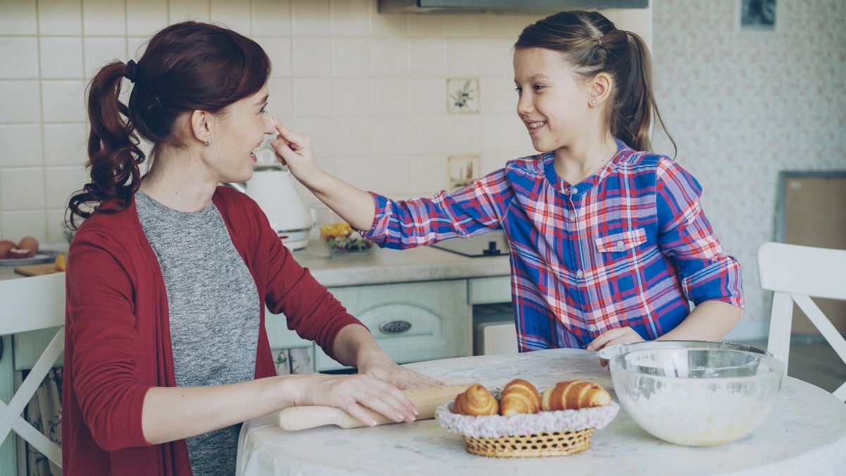 A parent and child laughing while baking together at a kitchen table — photo by Vitaly Gariev on Pexels