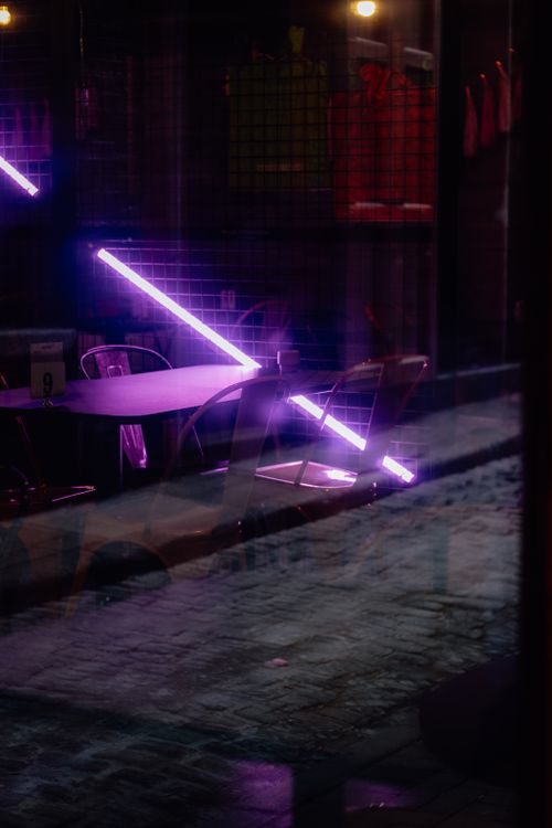 Free A moody urban scene in Ireland featuring neon purple lights reflecting on cobbled streets. Stock Photo