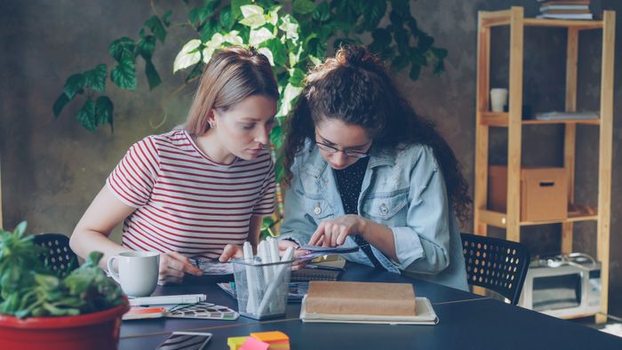 Two teammates working on a creative project at a desk — photo by Vitaly Gariev on Pexels