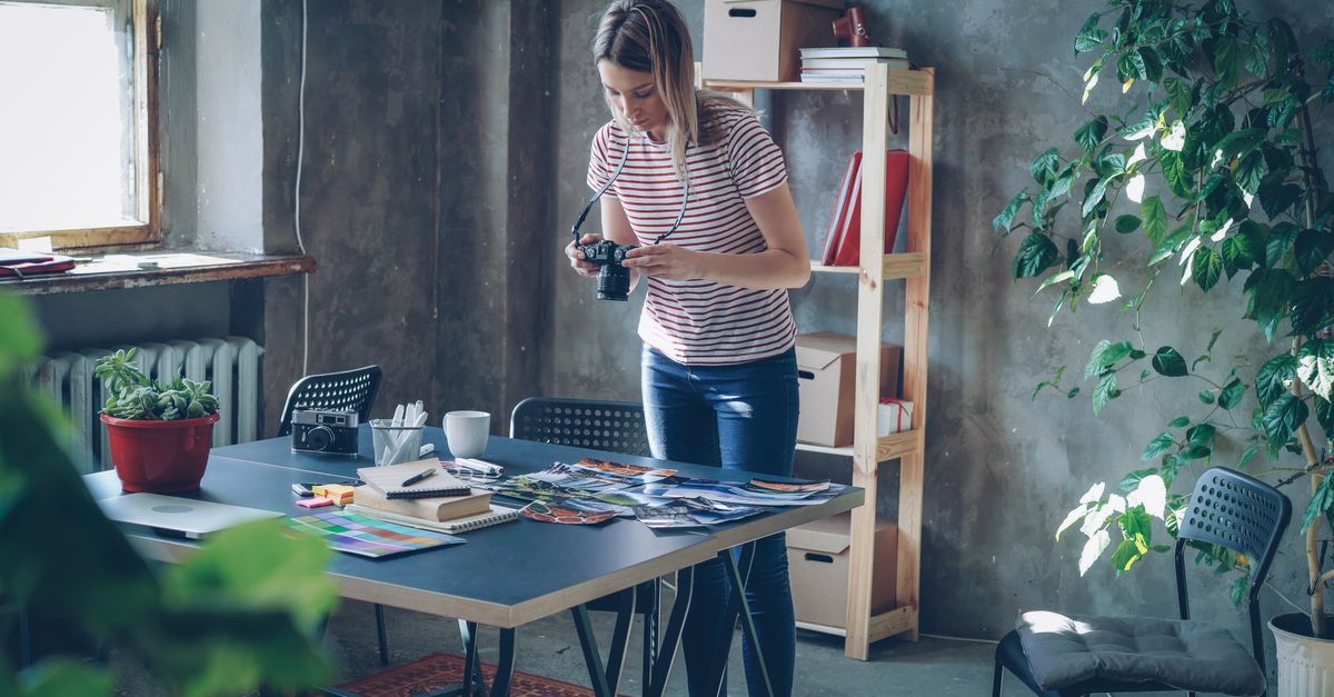 Young female photographer reviewing photos in an artistic studio setting.