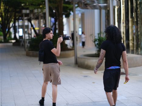 Two men in an urban setting, one holding a camera, capturing the essence of city life.