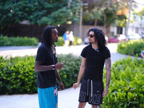 Two young men having a casual conversation on a sunny day outdoors.