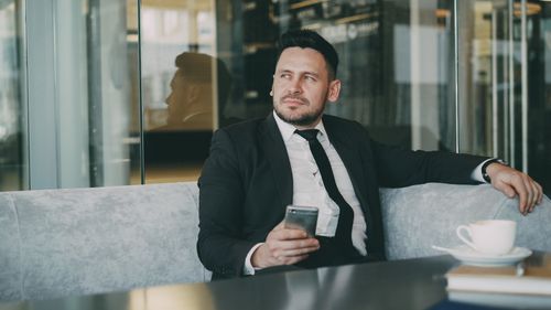 Free Professional businessman in a cafe holding a smartphone and enjoying coffee. Stock Photo