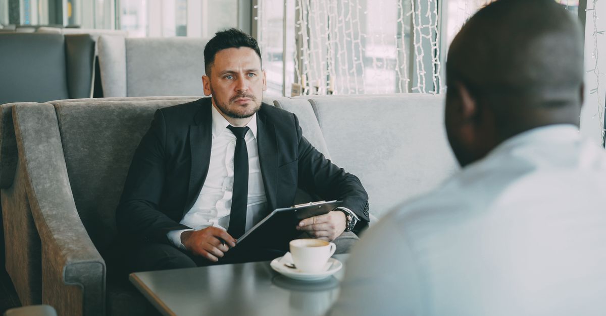 Two businessmen having a serious conversation over coffee in a stylish cafe setting.