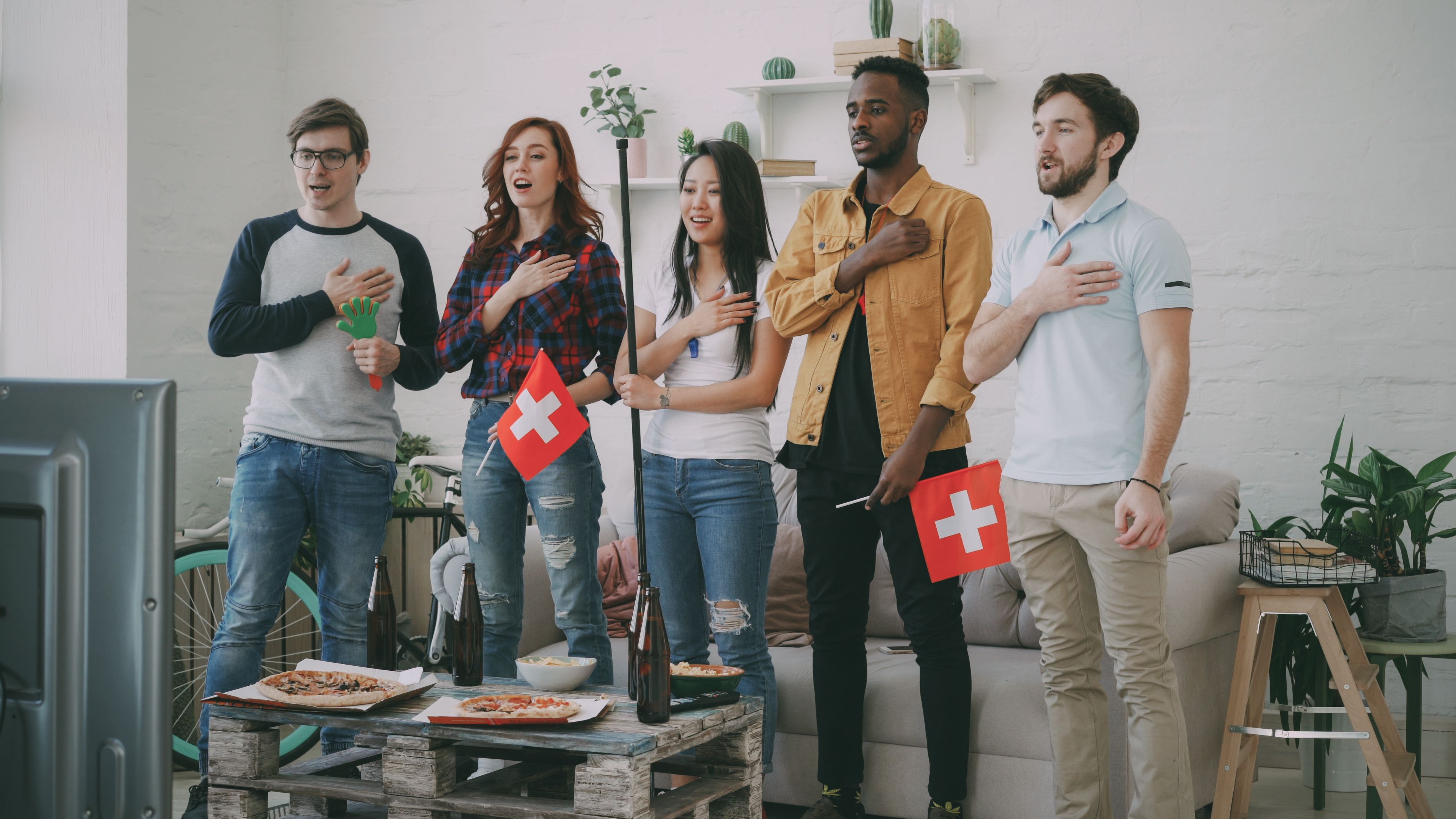 Groupe de personnes avec drapeau suisse regardant la télévision